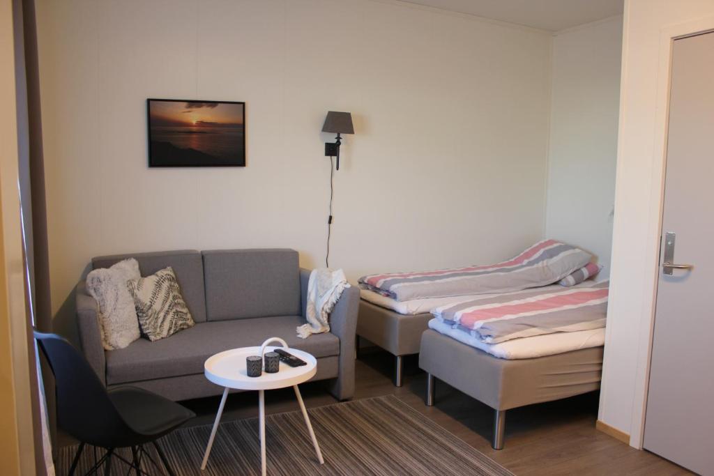 Bø i VesterålenJoker Bø的客房设有两张床、一张沙发和一张桌子。
