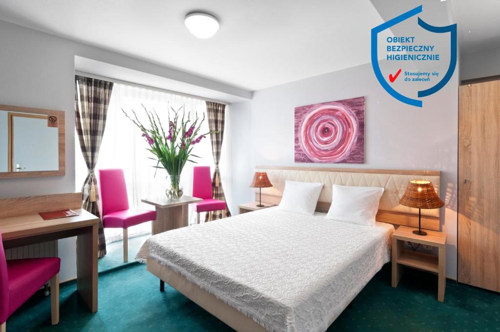 克拉科夫佩特鲁斯酒店的酒店客房,配有一张床和两张粉红色的椅子
