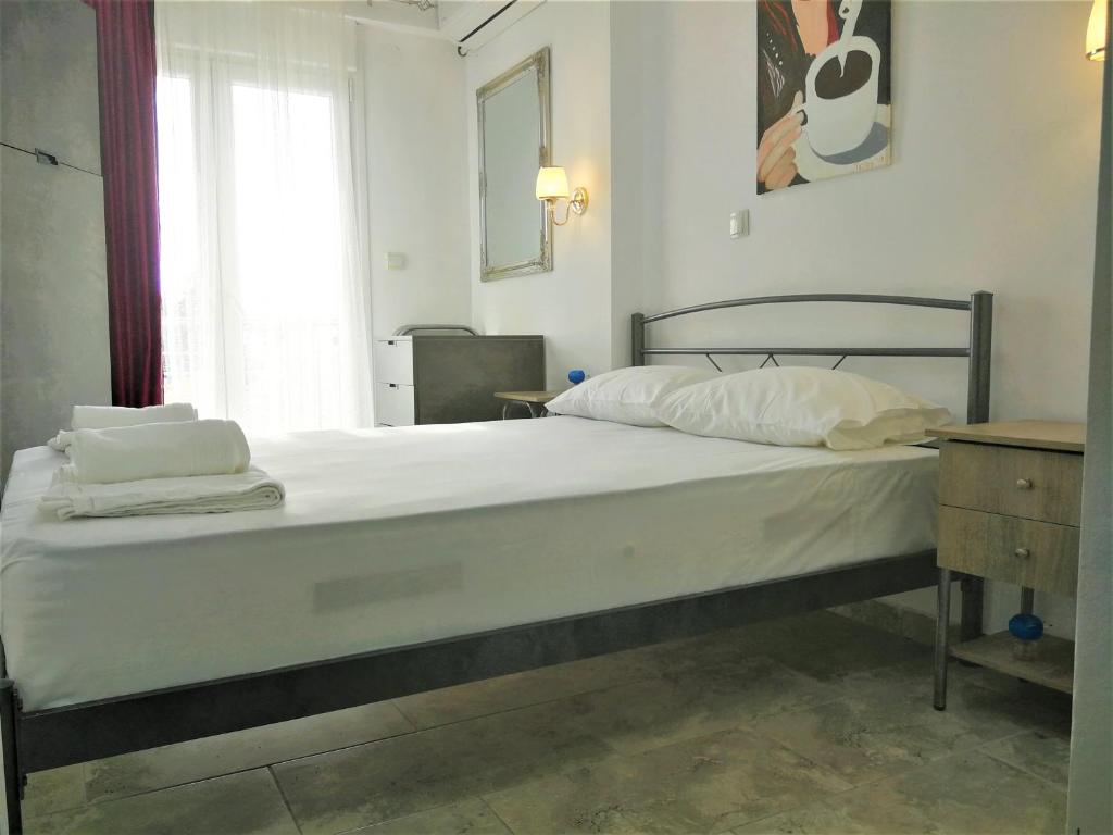 尼亚·卡利克拉提亚Artistic Rent Rooms & Apartments的卧室内的一张带白色床单和枕头的床
