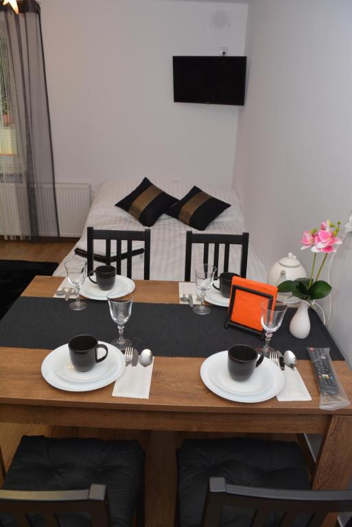 比亚瓦波德拉斯卡Apartamenty Kometa的一张带盘子和玻璃杯的木桌和一张床