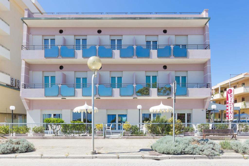 里米尼雷登斯酒店的一座大型粉红色建筑,设有蓝色阳台