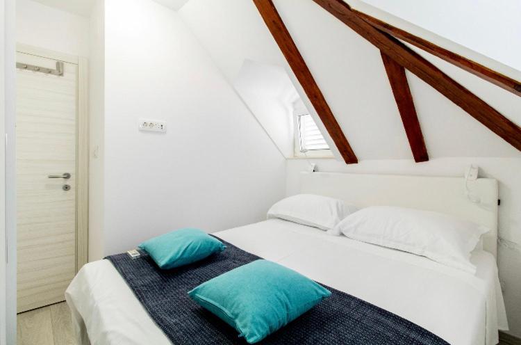 杜布罗夫尼克Apartman Roseta的客房内的白色床和蓝色枕头
