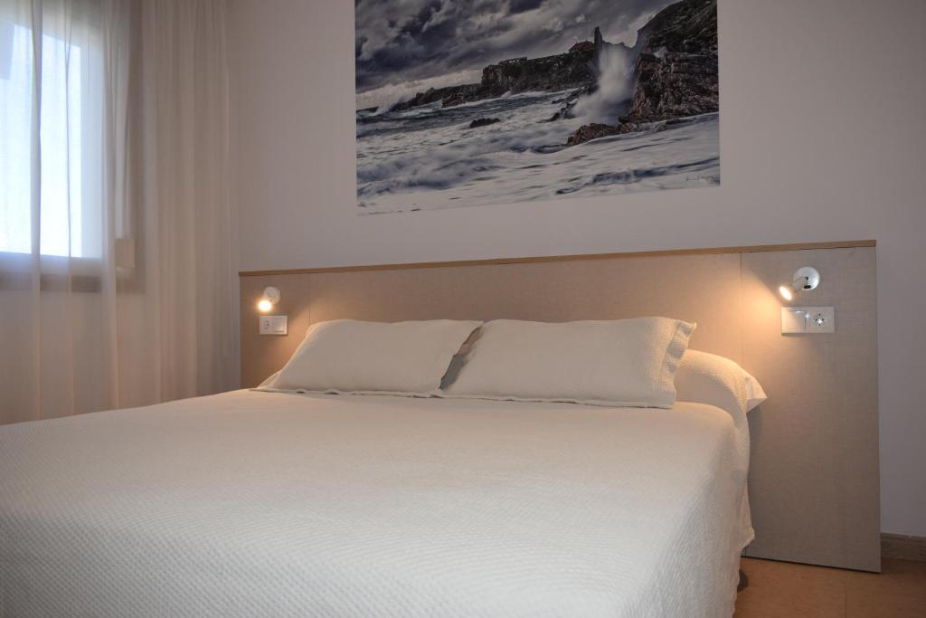 桑亨霍Apartamentos VIDA Versus的卧室配有一张白色床,墙上挂有绘画作品