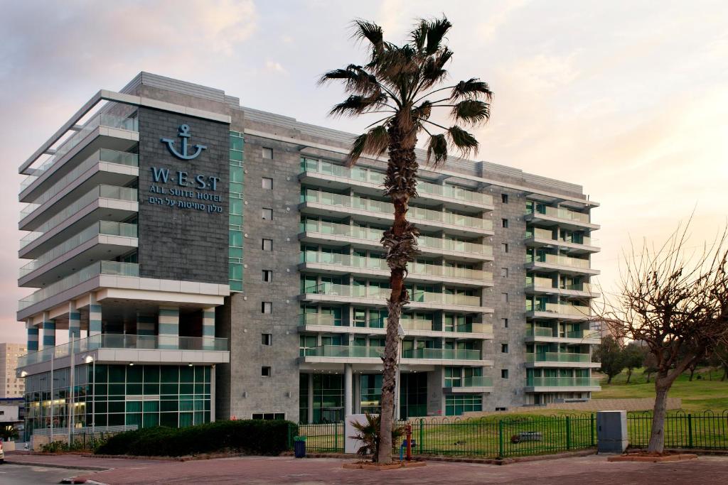 阿什杜德West All Suites Hotel Ashdod的前面有棕榈树的建筑