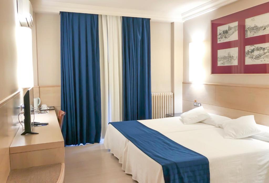 阿尔内多维尔雷酒店的酒店客房,配有床和蓝色窗帘