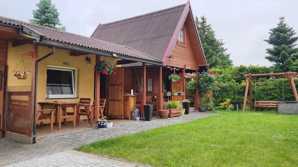 斯蒂格纳Domek Wakacyjny Kacperek Drewniany的房屋设有带桌椅的庭院