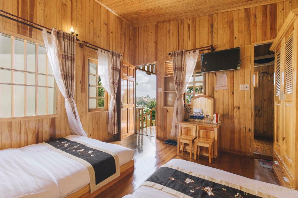 大叻Danh Tien Villa的一间卧室配有两张床和电视。