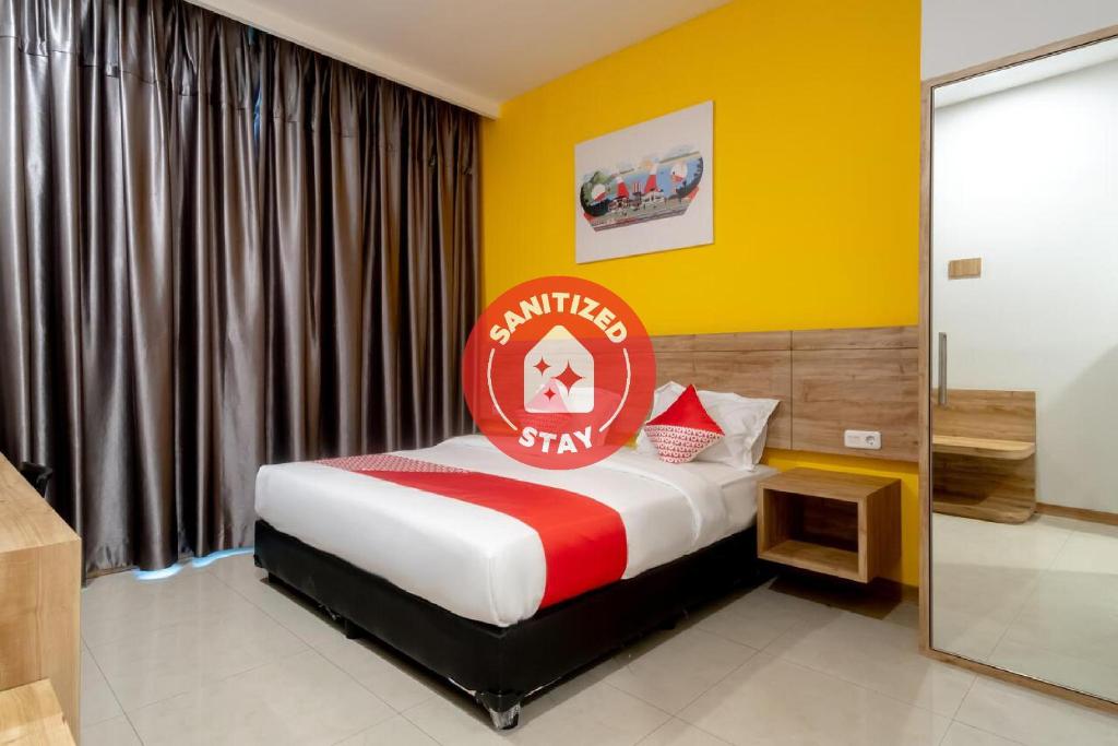 棉兰Super OYO 3159 Festive Inn的一间卧室,床上有红色标志