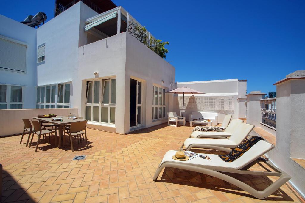 加的斯Casa Palacio Cádiz by Luxury Suites Cadiz的露台配有躺椅和桌椅。