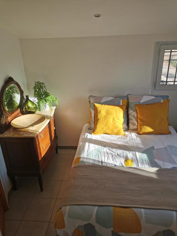 勒吕克Studio de charme en Provence的一间卧室配有一张带黄色枕头和桌子的床