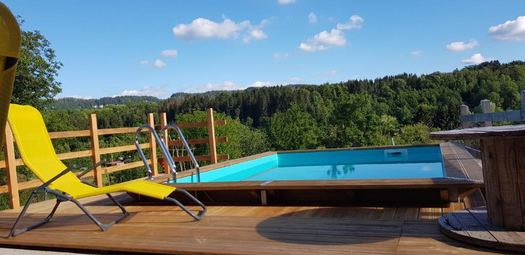 BonlieuLe Jura en toutes saisons piscine, SPA, climatisation, balades 2cv的一个带滑梯和椅子的甲板游泳池