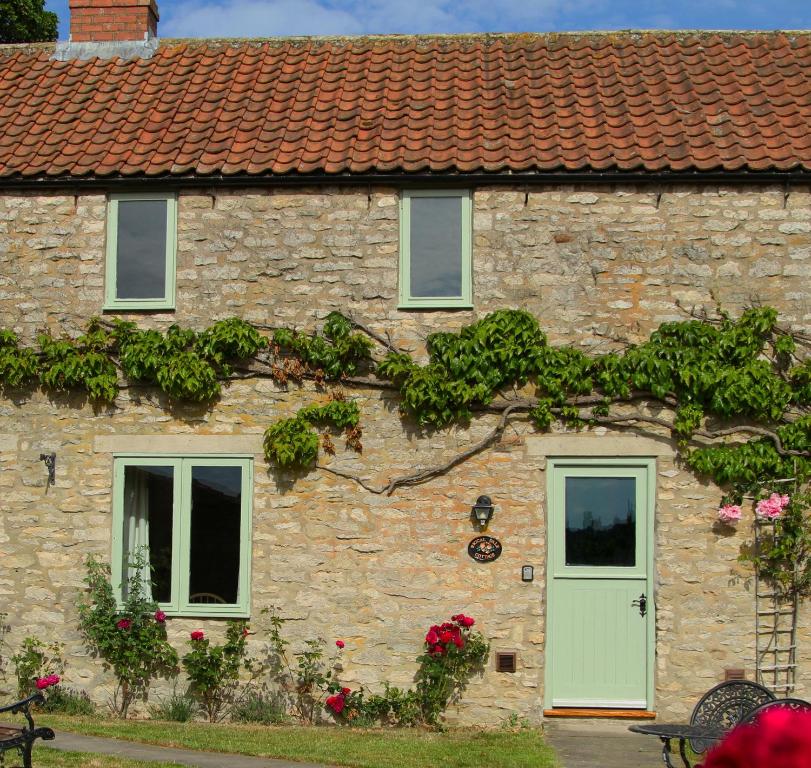 赫尔姆斯利Riccal Dale Cottage的一座石头房子,设有绿色的门和窗户