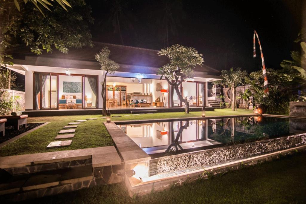 新加拉惹Villa Madja的一座晚上设有游泳池的房子