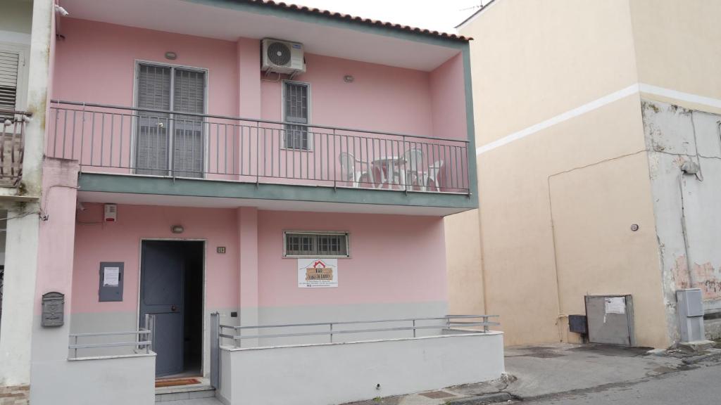 泰卡斯B&B Casa Di Lauro的一座粉红色的建筑,上面设有阳台