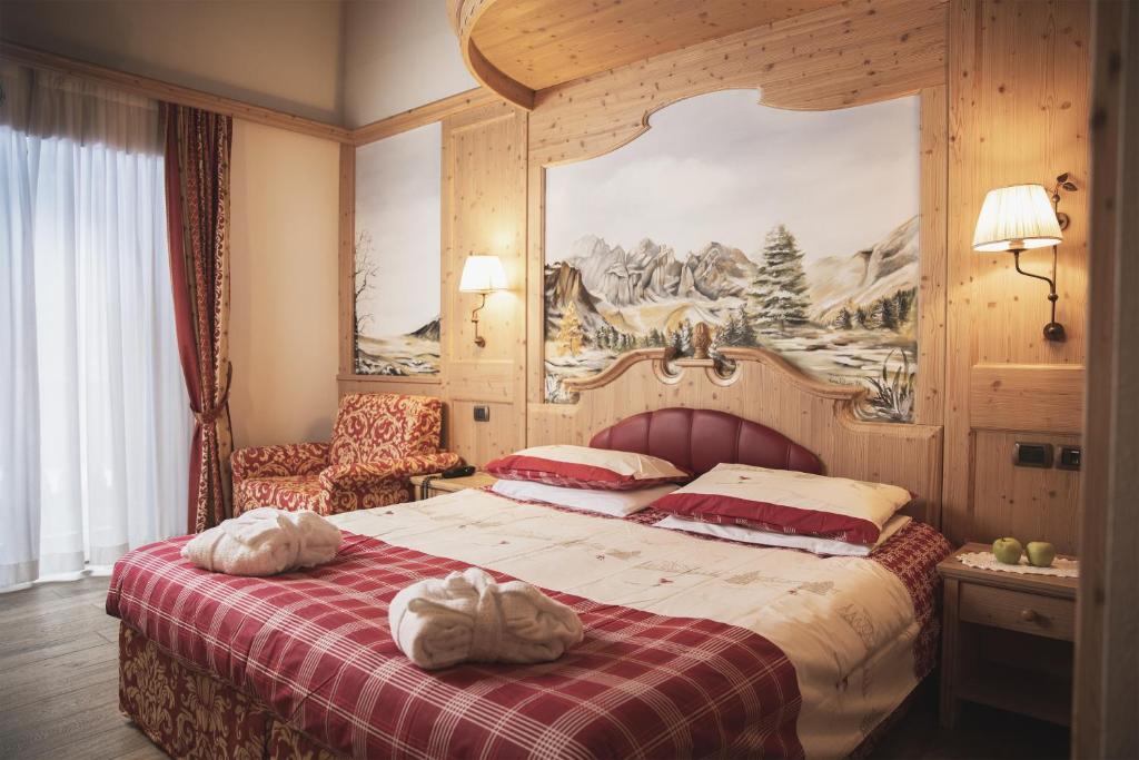 坎皮泰洛迪法萨Hotel Rubino Deluxe的一间卧室配有一张带红白毯子的床