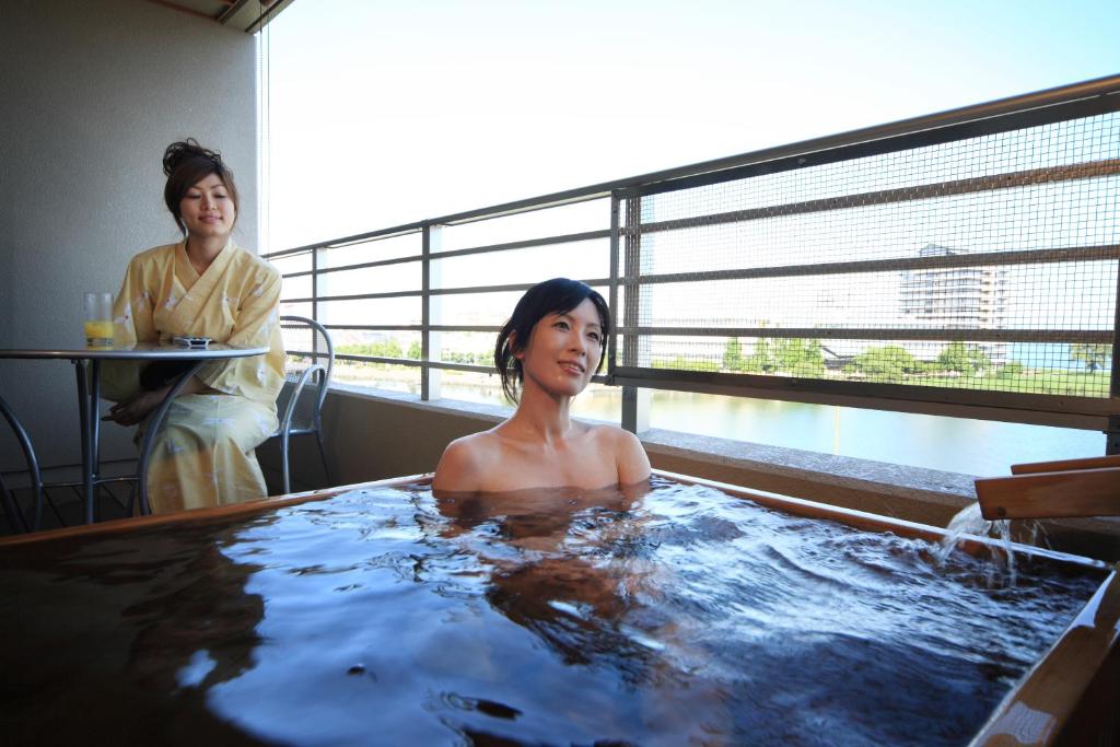 大津琵琶湖绿水亭酒店的坐在一个房间热水浴缸中的女人