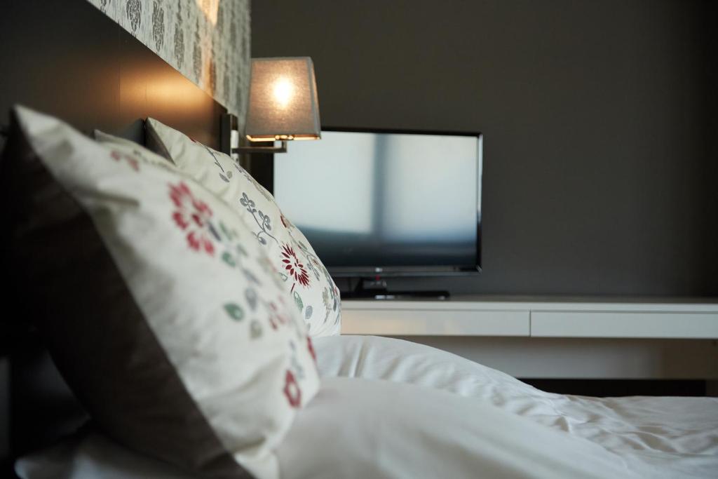 科特赖克Focus Boutique的一间卧室配有一张带电视和枕头的床。