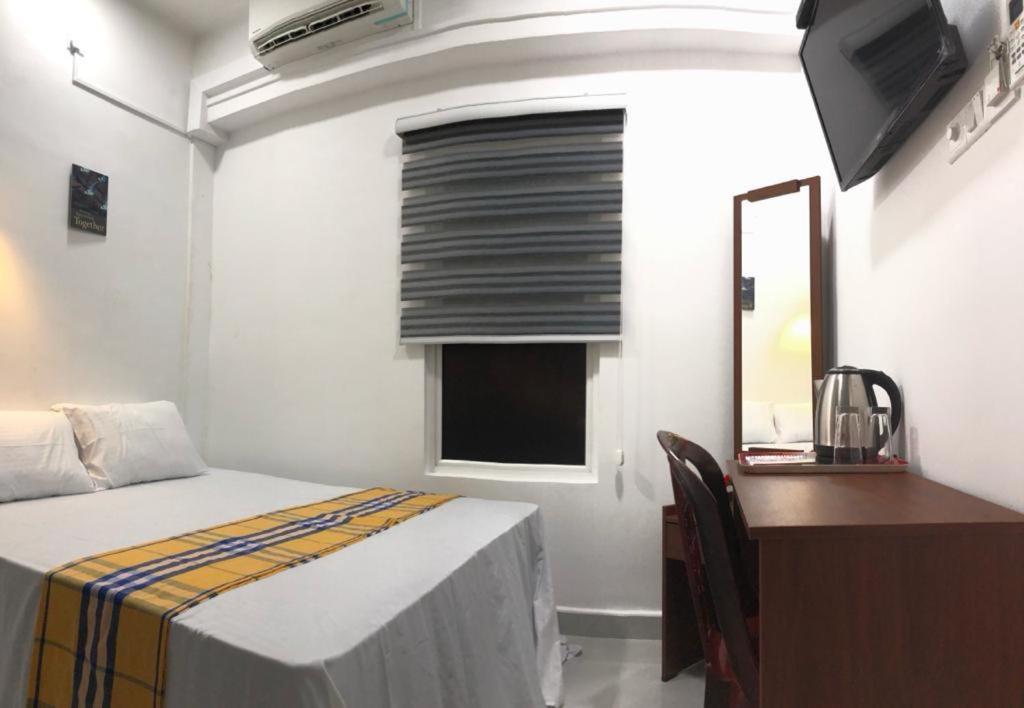 科伦坡WISH RESIDENCE SEASIDE Colombo3的一间卧室配有一张床、一张书桌和一面镜子