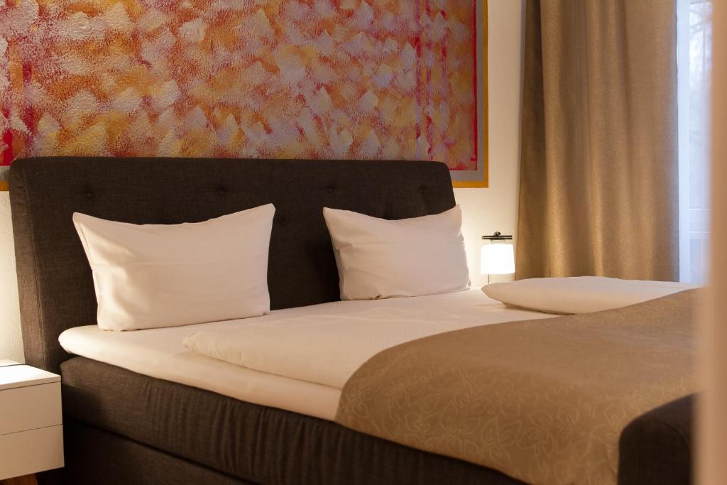 柏林库弗斯藤达姆斯普瑞维特兹酒店的一间卧室配有一张带白色枕头的床和一幅画