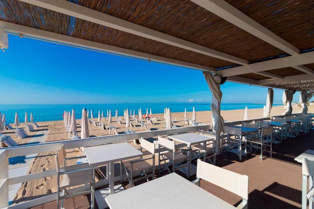 丽都玛里尼Hotel Club Ravezzo的餐厅设有白色的桌椅,享有海滩美景。