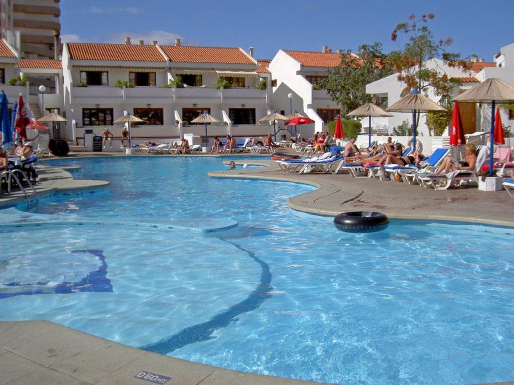 美洲海滩Nice apartment on Las Americas Beach的度假村内的大型游泳池,人们坐在椅子上
