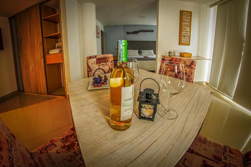 里奥内格罗Hotel Llanogrande Airport的木桌上的一瓶葡萄酒和玻璃杯