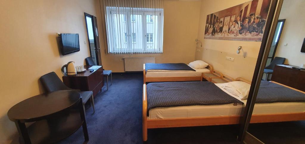 波兹南潘塔格斯旅馆的客房设有三张床、一张桌子和一台电脑