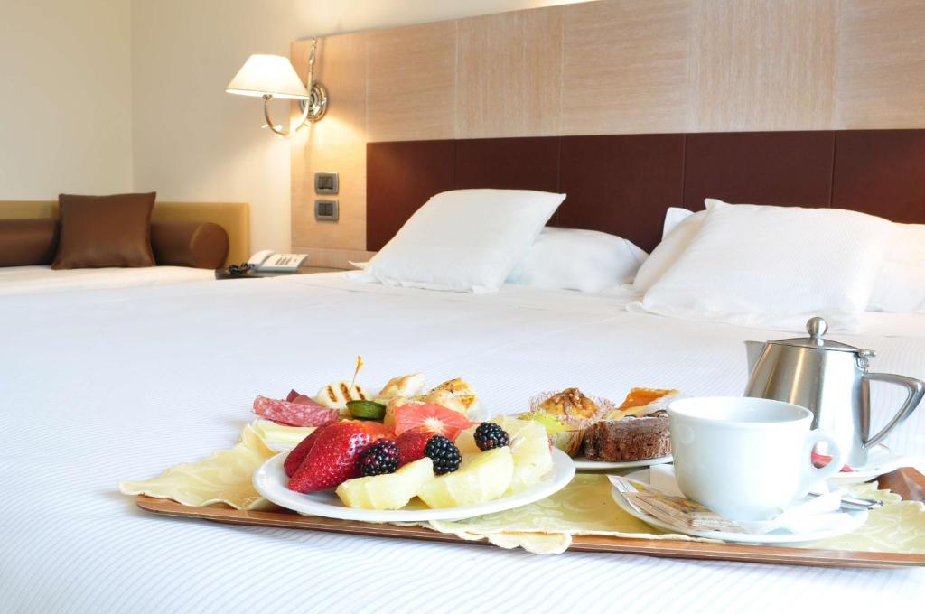弗利San Giorgio, Sure Hotel Collection by Best Western的床上的水果盘和咖啡