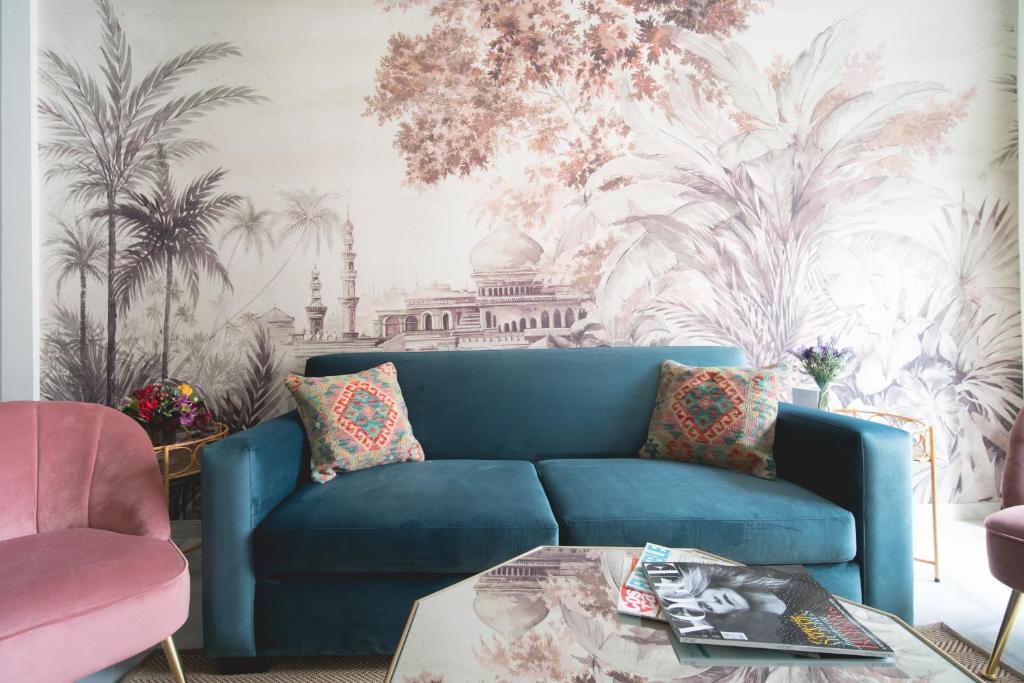 塞维利亚Arco Macarena Suite的客厅里一张蓝色的沙发,配有棕榈壁画