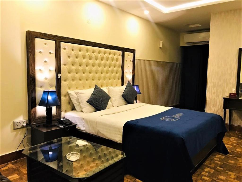 伊斯兰堡Atlas hotel的一间卧室设有一张大床和一张玻璃桌