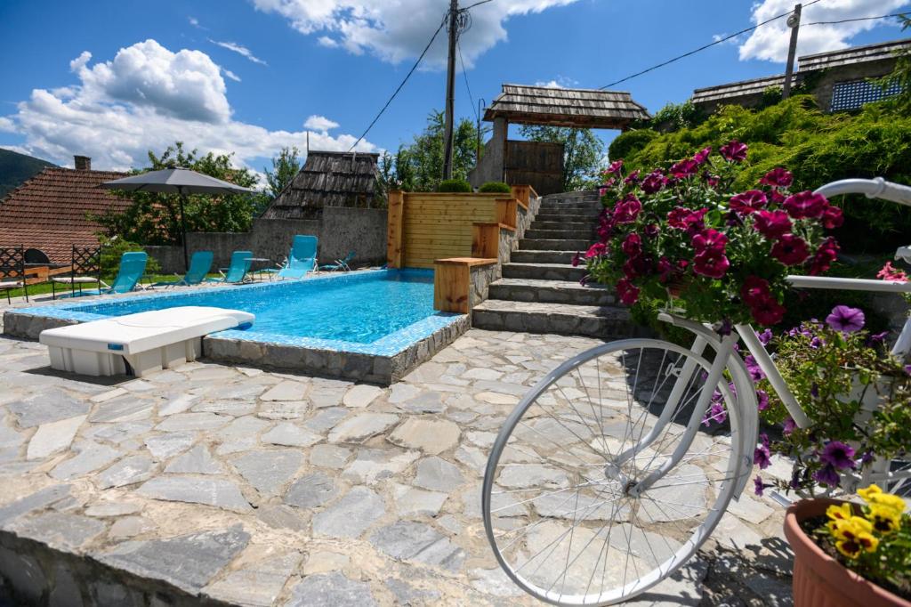 莫克拉戈拉Neva sobe sa pogledom na planine的一辆自行车停在一个鲜花盛开的游泳池旁