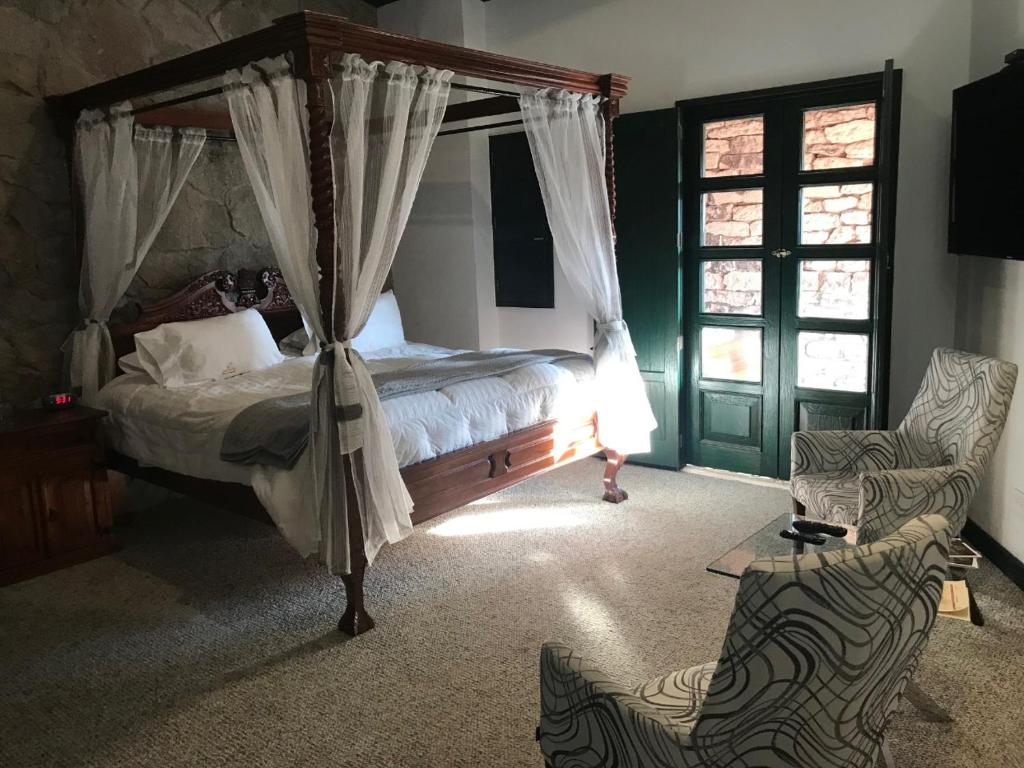 SanteaguedaHotel Canaria的一间卧室配有一张天蓬床和一把椅子