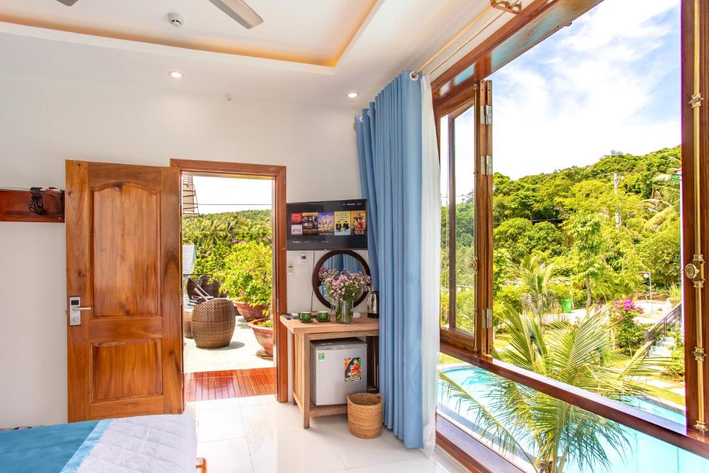 富国Caesar Phu Quoc Hotel的一间卧室设有大窗户,享有花园的景色