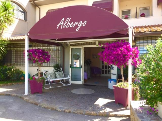 阿尔比尼娅Hotel La Rosa Dei Venti的大楼前的一间商店,上面有紫色的雨伞