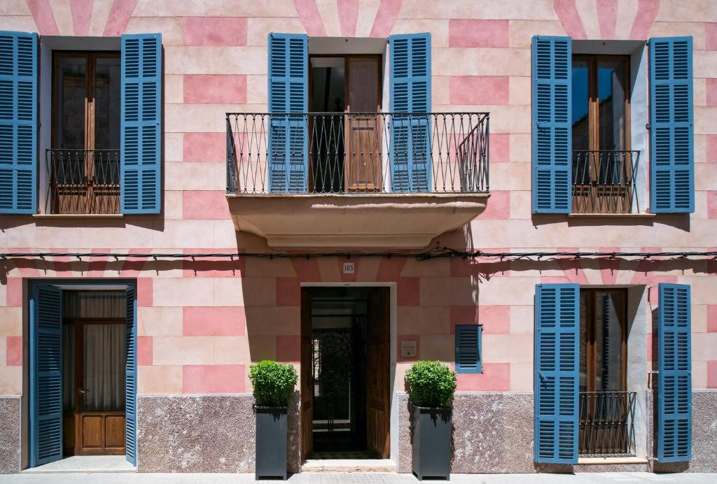锡内乌Es Picarol Sineu的粉红色的建筑,设有蓝色百叶窗和窗户