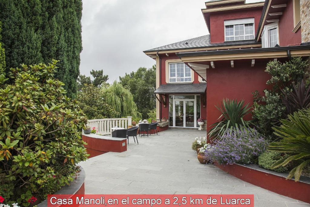 AlmuñaCasa Manoli Luarca的红色的房子前面设有庭院
