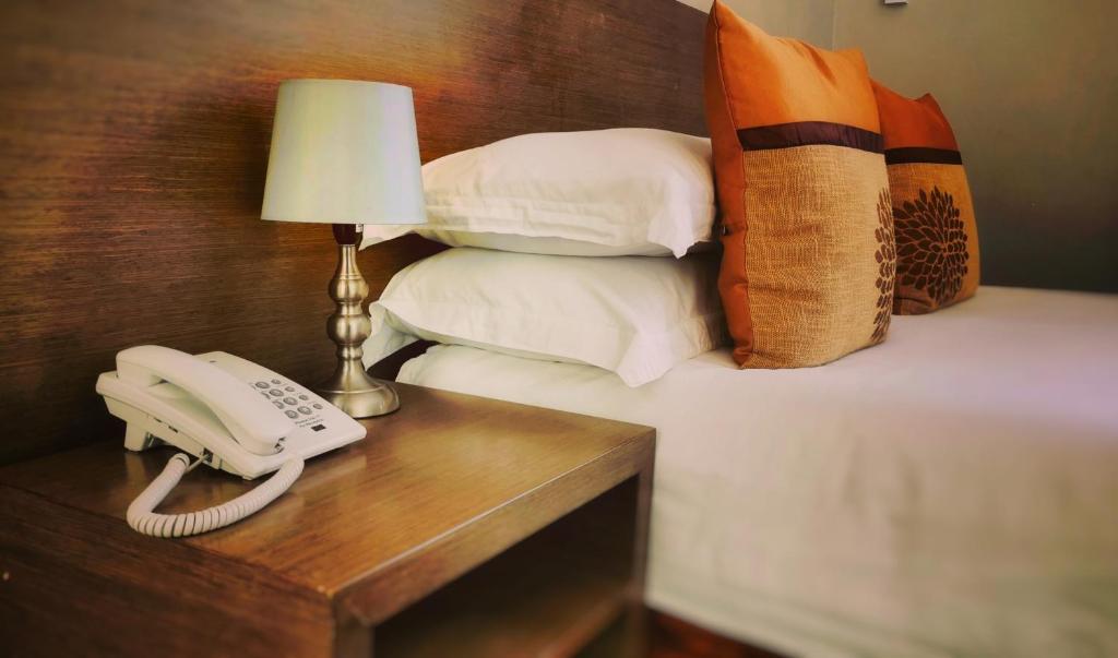 马普托Stay Inn - Guest House的一张桌子上的电话,床边有枕头
