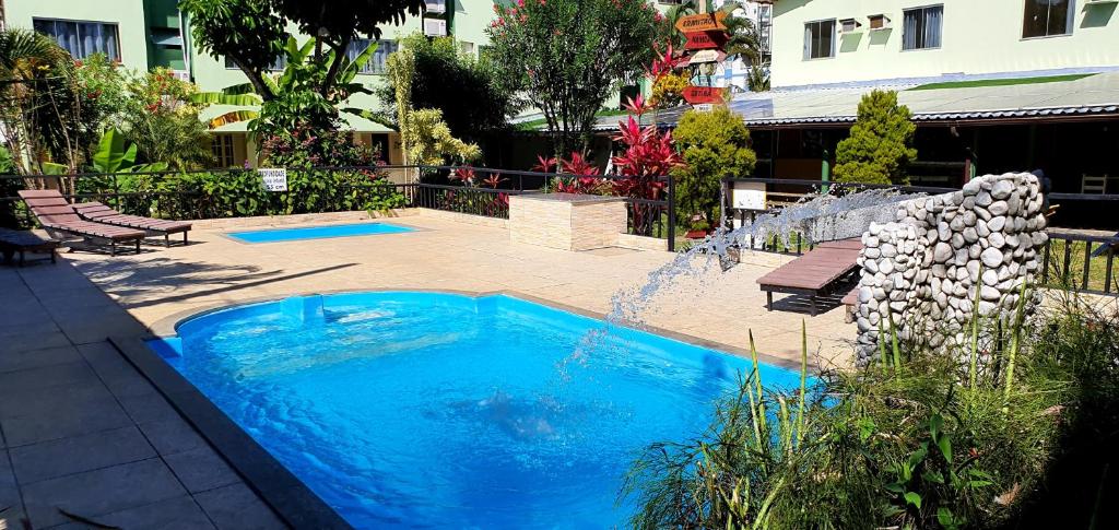 瓜拉派瑞Duas Praias Hotel Pousada的一座大型蓝色游泳池,在庭院里设有喷泉