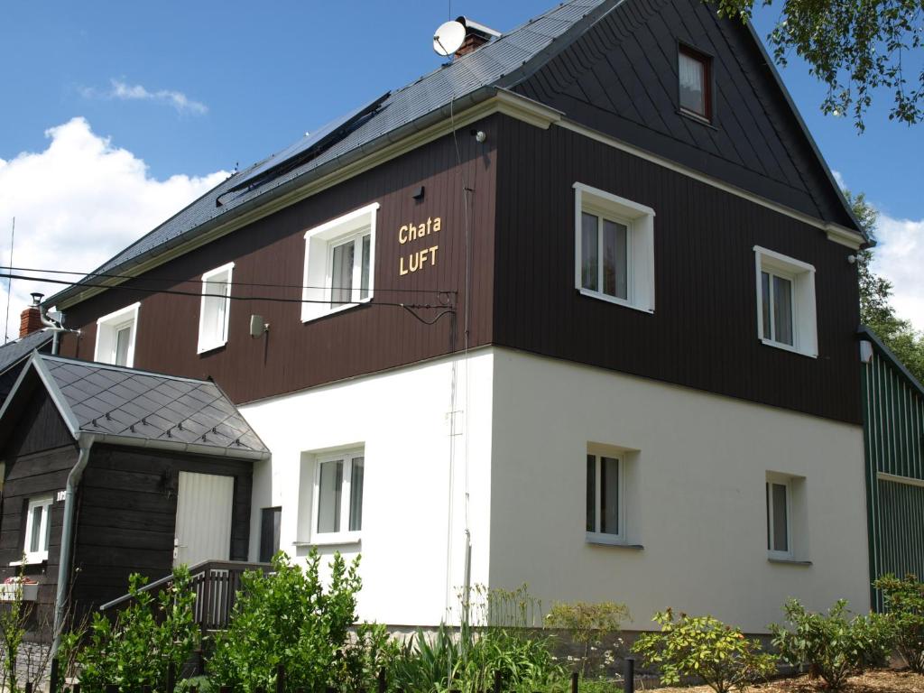 SněžnikGuest House LUFT Sněžník的白色和棕色的房子,有黑色的屋顶