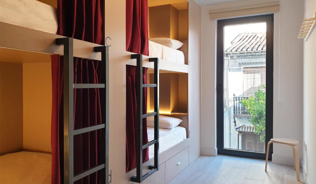 格拉纳达Broz Hostel的带双层床的客房,位于带窗户的房间内
