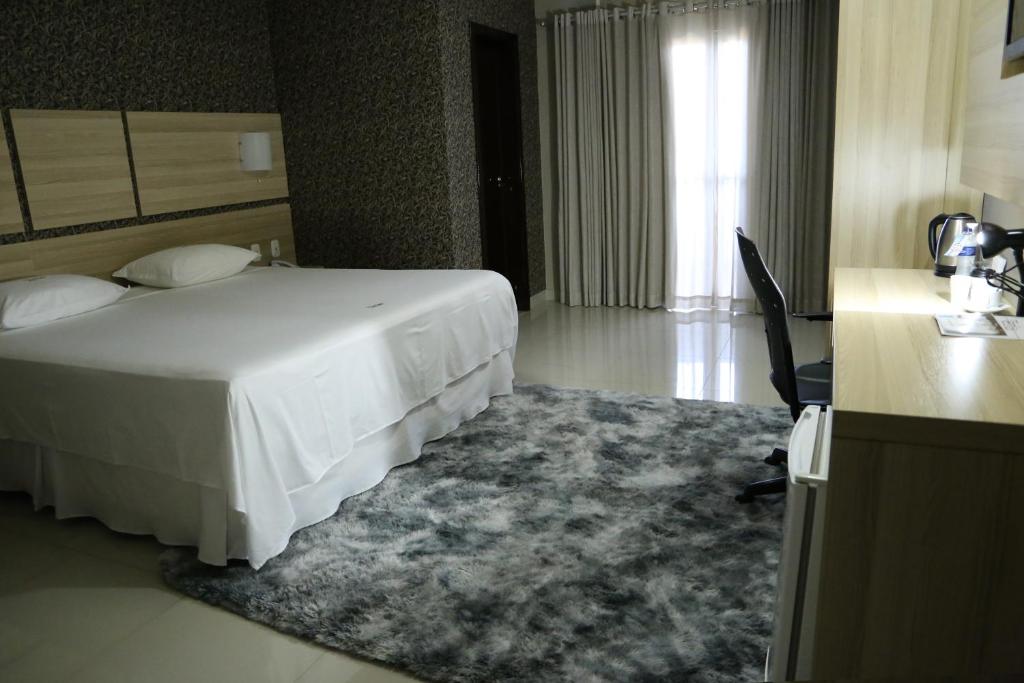 东普里马韦拉Tezla Hotel的酒店客房配有一张白色的床、一张书桌和一张书桌。