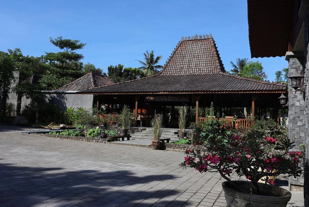 婆罗浮屠Amata Borobudur Resort的庭院中一座带花屋顶的建筑