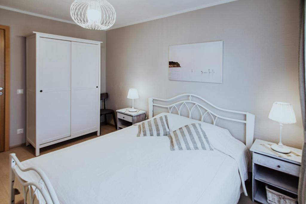 尤卡尔内Lina apartamenti的卧室配有白色的床和吊灯。