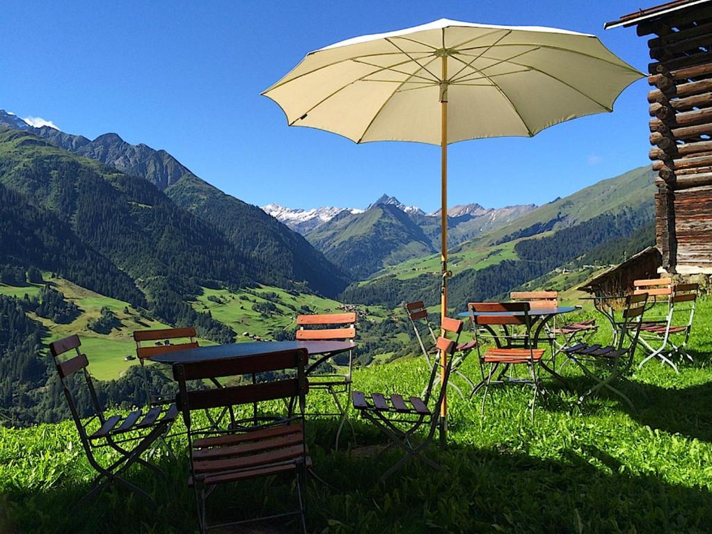 Lumbrein阿里皮纳尔酒店的山中带遮阳伞的桌椅