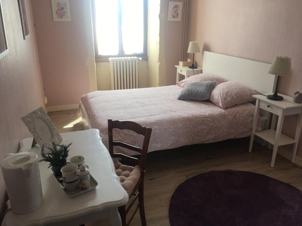 ArandasAuberge à la Vieille Cure的卧室配有1张床、1张桌子和1把椅子