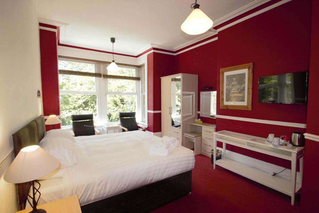 哈罗盖特山谷酒店的红色的卧室设有白色的床和窗户。