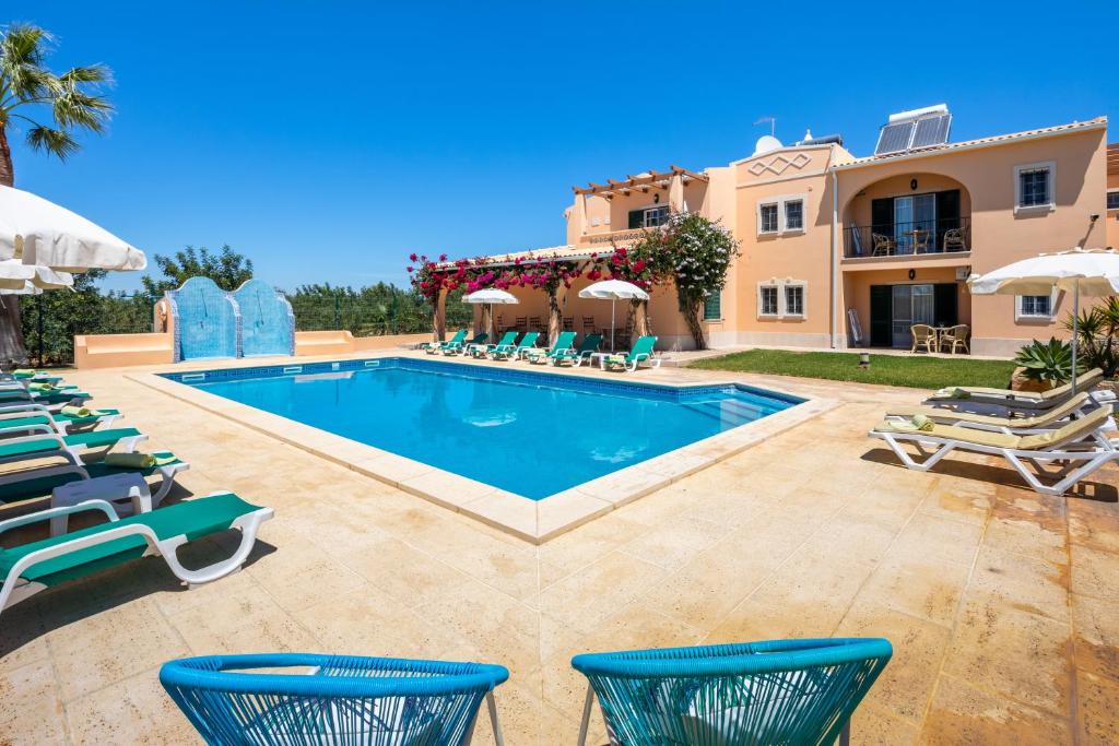 阿尔布费拉Apartamentos Monte dos Avós, Albufeira的别墅设有游泳池和庭院家具。