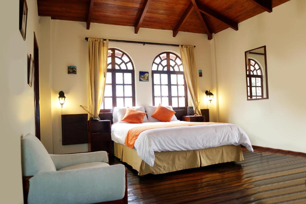 基多Kitu Hotel的一间卧室设有一张大床和两个窗户。
