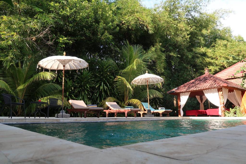 特贾库拉Villa Aditya的游泳池旁设有椅子和遮阳伞
