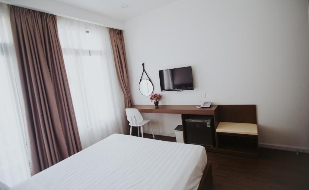 绥和市Marina Hotel Phú Yên的配有一张床和一张书桌的酒店客房